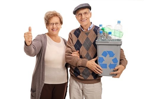 Happy old couple holding a recycling bin