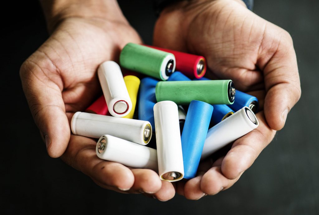 Close up of hands holding batteries (a common recycling contaminant)