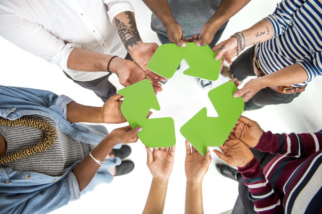 group of people holding recycling arrows