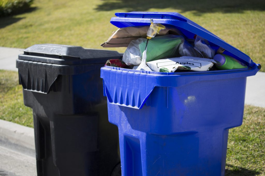 Overflowing Recycling bin next to a garbage bin