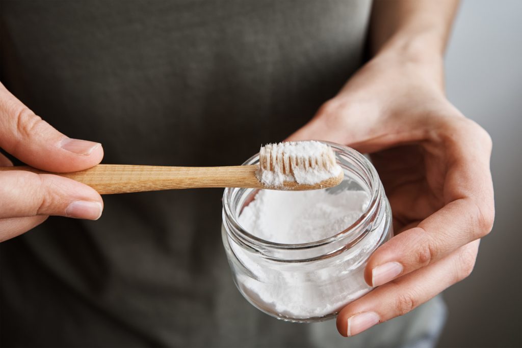 Woman holds bamboo toothbrush and tooth powder. Zero waste and ecological products concept