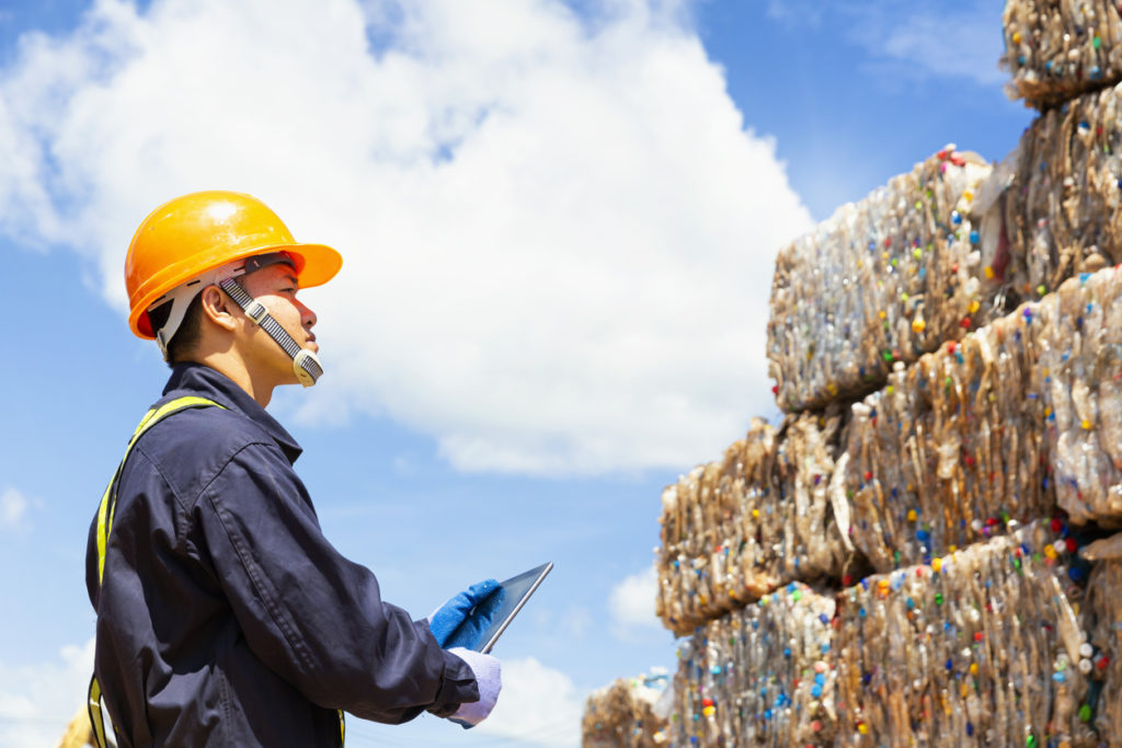 Engineer and recycle. Engineers standing in recycling center. Male foreman wearing protective equipment and holding tablet.