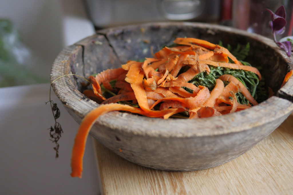 Wooden bowl filled with carrot peelers for composting