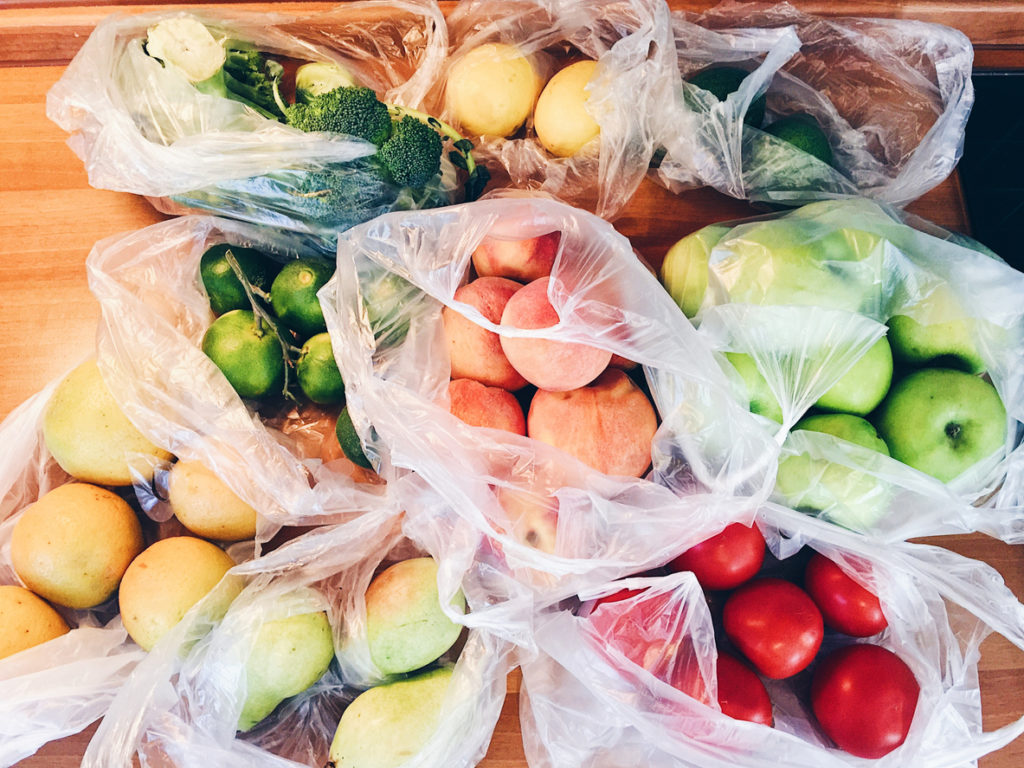 Apples, peachs, tomatoes, pears, cucumbers, avocado packed in plastic bags after shopping at local market 