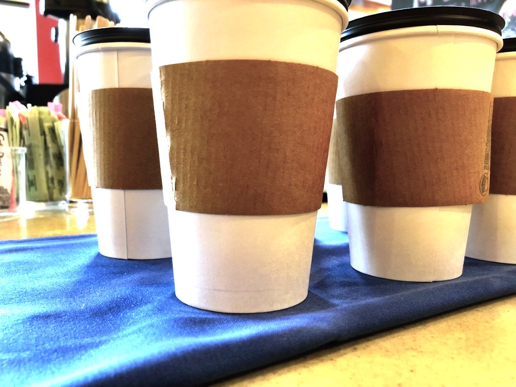 close up of disposable coffee cups with cardboard sleeves