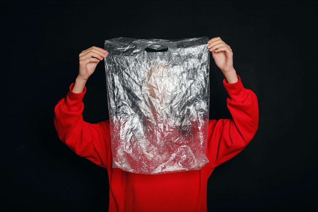 Person holding up a clear plastic bag which is not an accepted recycling item in home bins