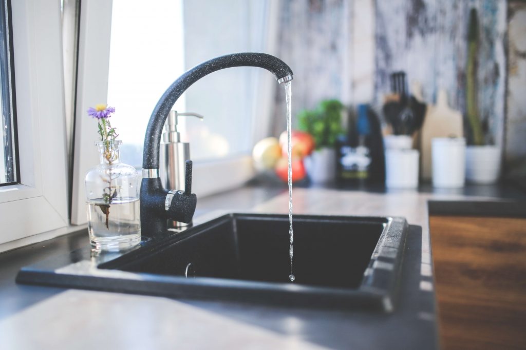 Kitchen sink running water to show recycled containers must be cleaned in order to avoid contamination