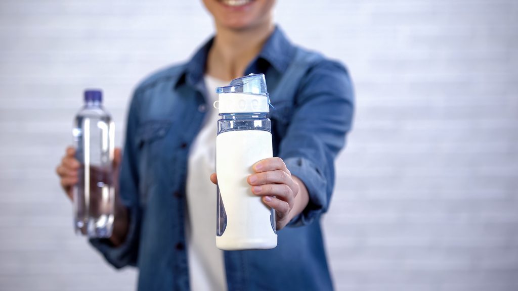 woman choosing a reusable water bottle instead of a disposable plastic water bottle