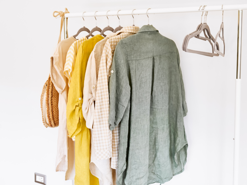 a clothing rack with only a few pieces of clothing, a few hangers, and a purse on it