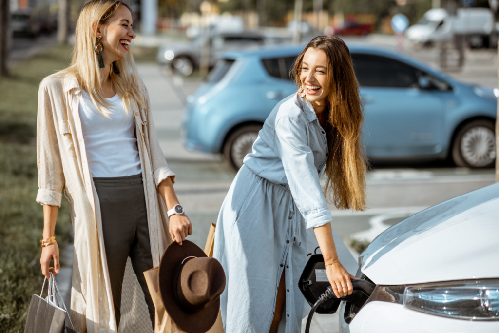 Woman plugging charging gun into the electric car in the parking lot outdoors