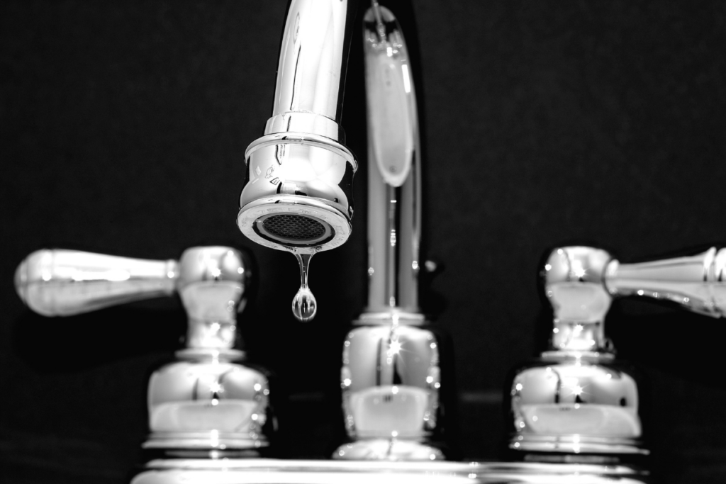 close up of a sink faucet with a drip of water coming out