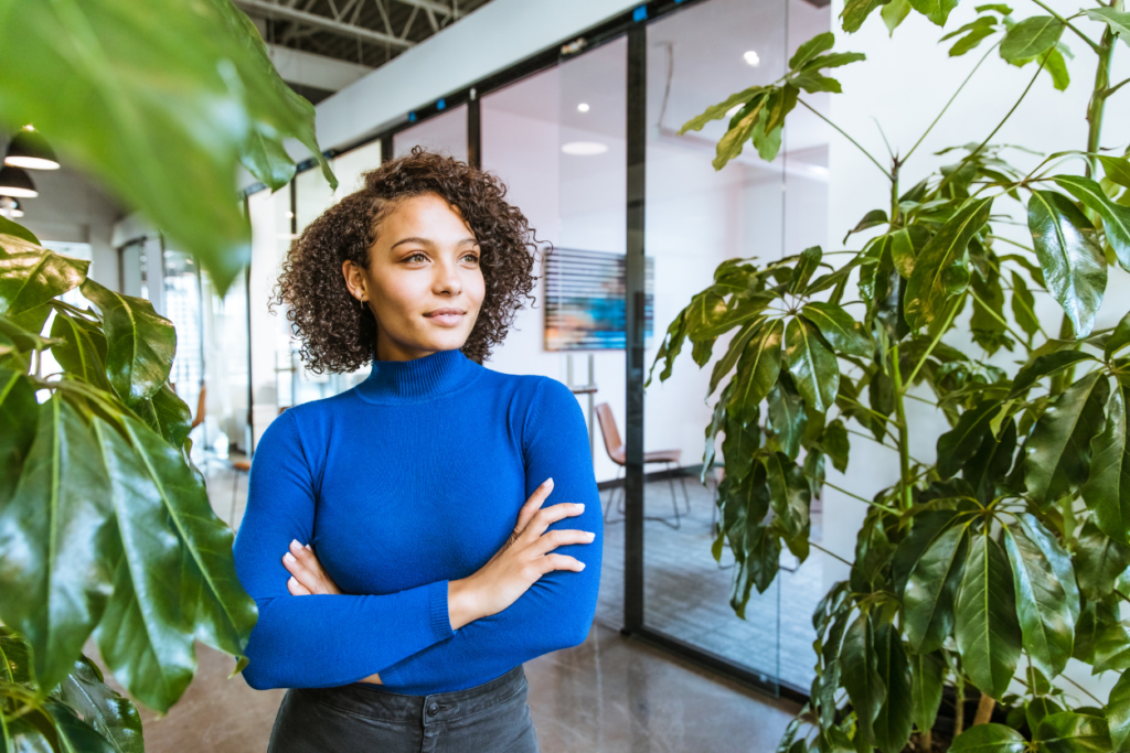 Woman in blue shirt standing in office with plants around her