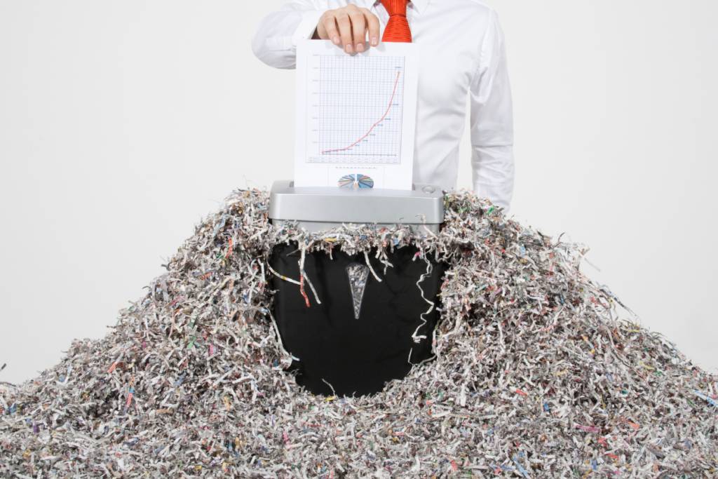 Office worker shredding paper into an overflowing mound of shredded paper