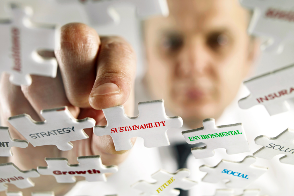 Business man putting the pieces of a puzzle together. Puzzle pieces all have key words connected to sustainability 