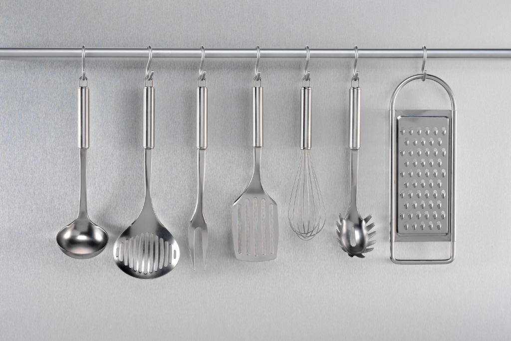 stainless steel cooking utensils hanging from a metal bar